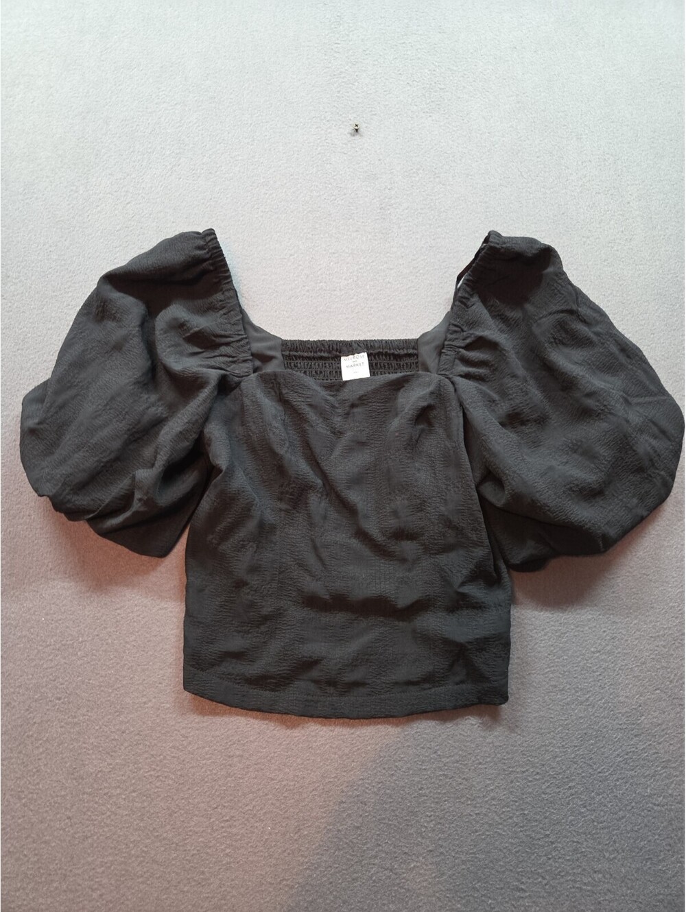 women's black blouse features a smocked square neckline and voluminous puff...